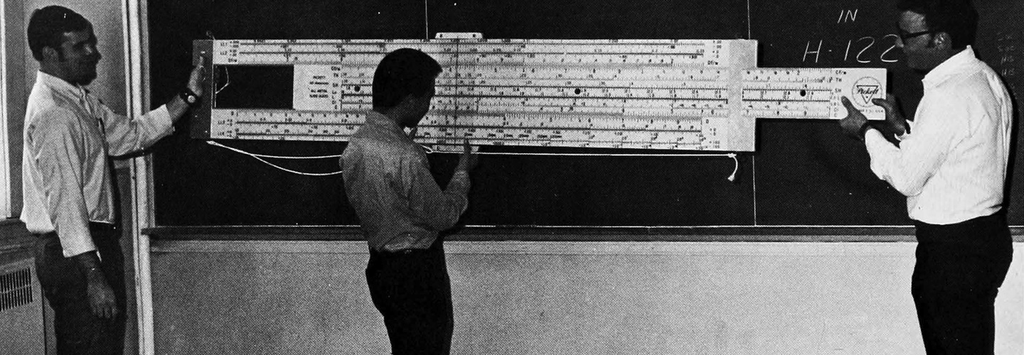 Students and professor operating a demonstration slide rule in 1970